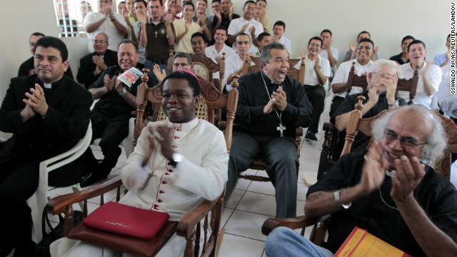 Fortunatus Nwachukwu, in white, the Vatican's ambassador to Nicaragua, applauds as he watches a local television station announcing the new pope with others in Managua, Nicaragua.