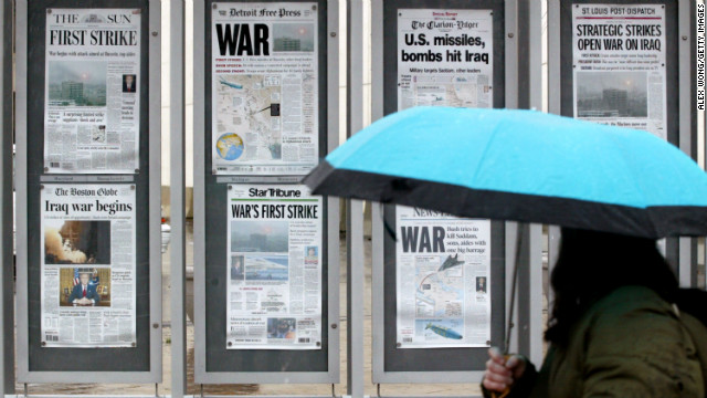 A pedestrian looks at front-page headlines on display outside the future site of the Newseum in Washington on March 20, 2003.
