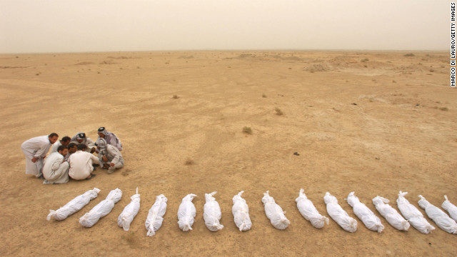Iraqi men check a list near the remains of bodies excavated from a mass grave on the outskirts of Al Musayyib on May 31, 2003. Locals said they uncovered the remains of hundreds of Shiite Muslims allegedly executed by Saddam Hussein's regime after their uprising following the 1991 Gulf War.