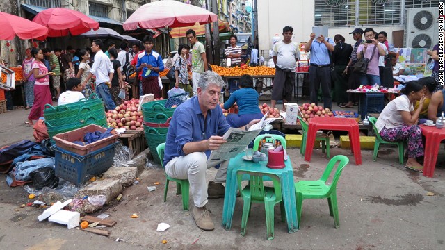 Anthony Bourdain reads the paper next to a local market in Yangon, Myanmar.