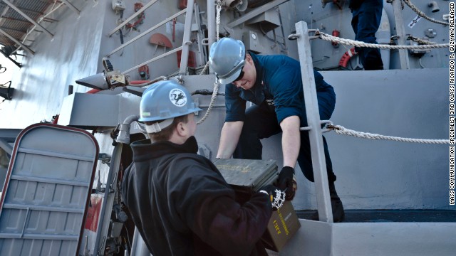 Fire Controlman 2nd Class Jason Titcombe, left, hands Fire Controlman 2nd Class Joshua Clements ordnance aboard the destroyer USS Lassen in this Navy handout photo taken on March 5.