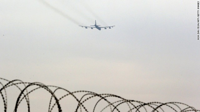 A B-52 bomber flies over the wire-topped fence of a U.S. air base in Osan, South Korea, on Tuesday, March 19.