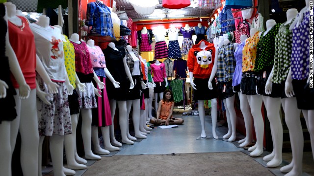  A woman sits in her shop lined with mannequins in a shopping center in Mawlamyine.