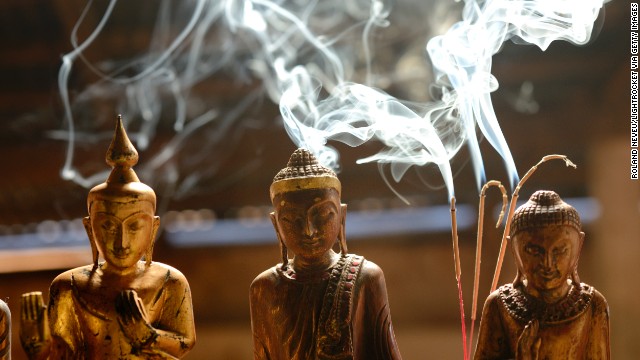 Wooden figures sit for sale as incense burns behind them at a stall in Indein, a village by Inle Lake.