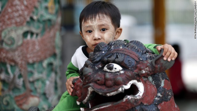 A Burmese boy climbs on a gargoyle statue at the sacred Shwedagon Pagoda in Yangon.