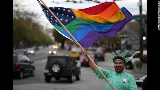 Nikolas Lemos waves a rainbow flag during Monday's rally in San Francisco.