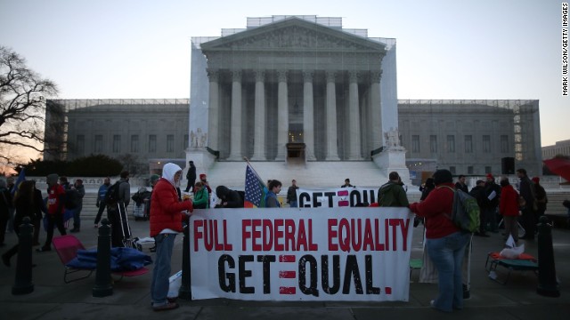 Banners are held up as people gather outside the Supreme Court on Tuesday.