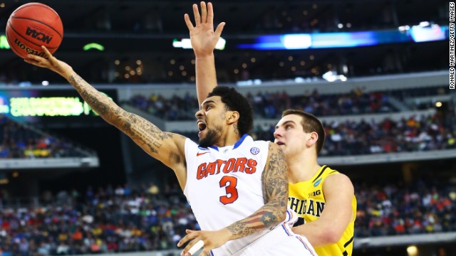 Mike Rosario of Florida shoots past Mitch McGary of Michigan.