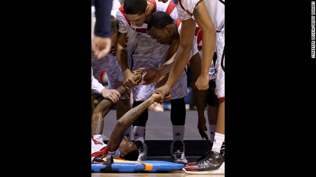 Kevin Ware, bottom left, is comforted by his teammates as his leg is examined by medical staff.