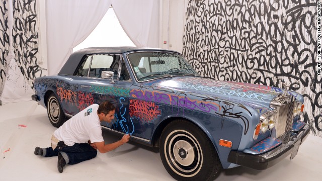 U.S. graffiti artist Jonone performs a painting on a Rolls Royce car owned by former Manchester United and France football player turned actor Eric Cantona during a television show.