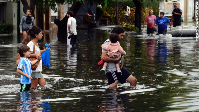 People wade through a flooded street after heavy rains in La Plata, Argentina, on Wednesday, April 3. The storm has claimed more than 50 lives in La Plata and nearby Buenos Aires, officials said.