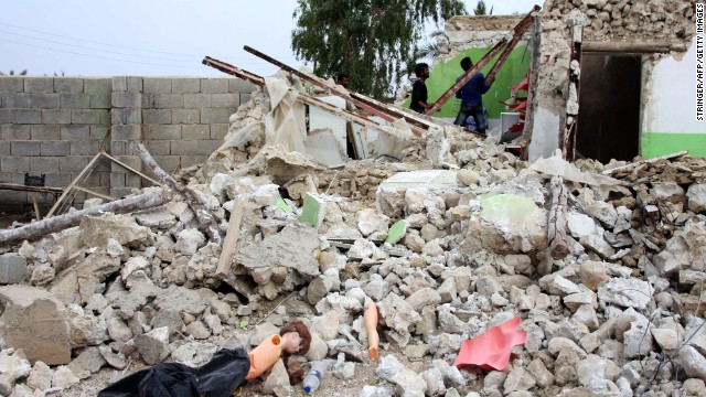 People survey a destroyed house in the village southeast of the Persian Gulf port city of Bushehr.