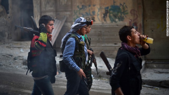 Syrian and Kurdish rebel fighters walk in the Sheikh Maqsud district of Aleppo on April 14.