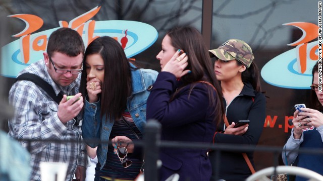 Bystanders check their mobile devices for news of the explosions.