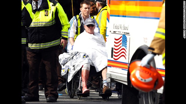 A runner in a wheelchair is taken from a triage tent after the explosions went off.