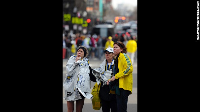 Racers and race officials stand by after multiple explosions near the finish line.