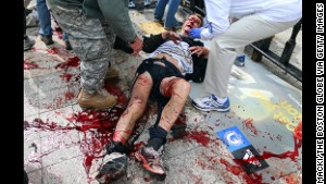 A victim of the first explosion is helped on the sidewalk of Boylston Street in Boston on Monday.