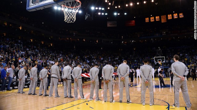 Players and fans observe a moment of silence before the San Antonio Spurs and Golden State Warriors NBA game in Oakland, California, on Monday.