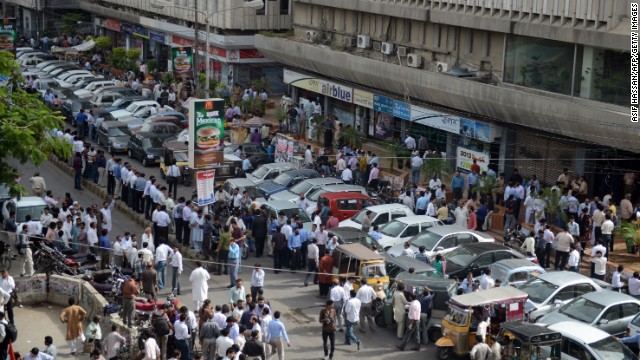 People stand outside after evacuating buildings following tremors in Karachi.