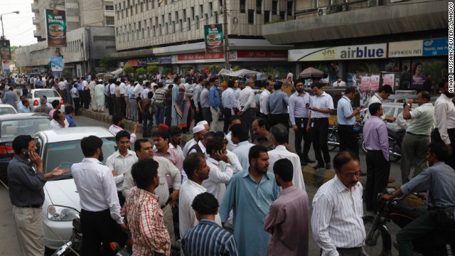 People stand outside their office buildings on Tuesday in Karachi.
