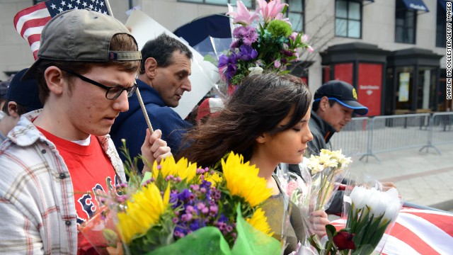 People walk along the barricade at Boylston Street on April 16, following yesterday's bomb attack on the Boston Marathon.