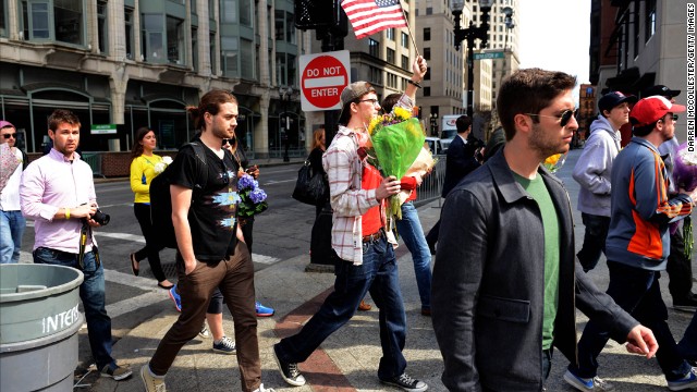 People walk Boylston Street where memorials have been set up to the corner of Berkeley after the barricades were moved back on April 16.