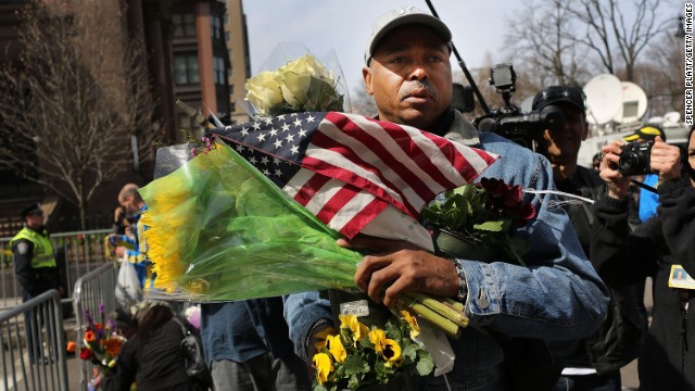 A man carries balloons, flowers and flags to a memorial for victims on April 16, just blocks from the scene of the bombings.