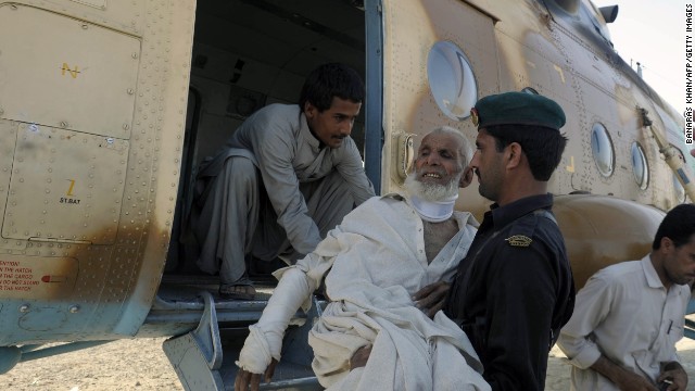 A Pakistani Frontier Constable carries an injured earthquake survivor into an army helicopter in Mashkell on Thursday.
