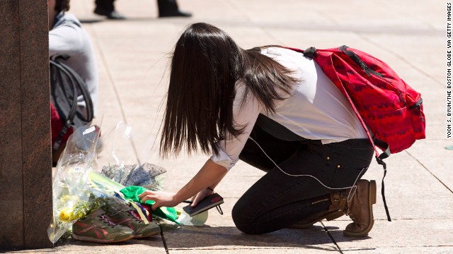 Joy Liu, 23, puts a green hat with a shamrock and a note with the words "From Boston and Beijing with love. RIP" at the memorial for Lu.