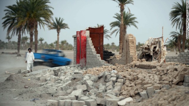 An earthquake survivor walks past a collapsed house in the Mashkell area of Pakistan's Baluchistan province on Thursday, April 18. The casualty count from an earthquake that struck near Pakistan's border with Iran stands at 35 dead and more than 150 injured, authorities said Wednesday.
