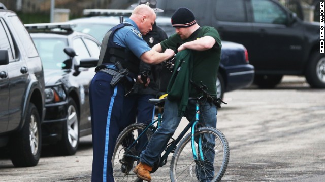 A Massachusetts State Police officer checks the bag of a cyclist amid heightened security on Friday in Watertown. 