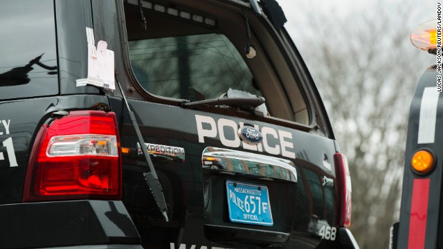 A Watertown police vehicle with bullet holes in its body and a shattered windshield is towed out of the search area on April 19 in Watertown, Massachusetts.