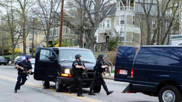 SWAT team members run toward a police assault on a house as gunfire erupts on April 19.