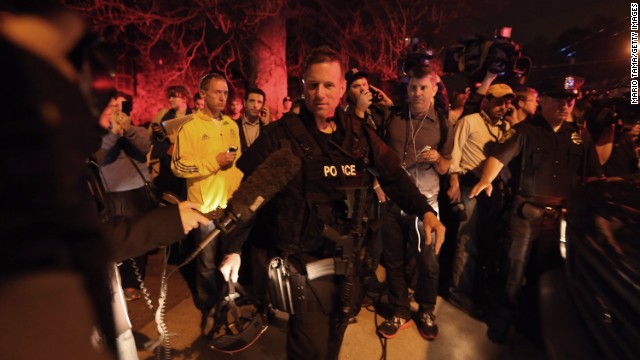 A SWAT team member is followed by reporters and a celebrating crowd on April 19 after the successful operation.