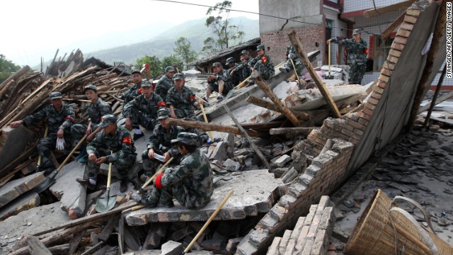 Rescuers sit on ruins of a house in Longmen, an area close to the epicenter of the earthquake.
