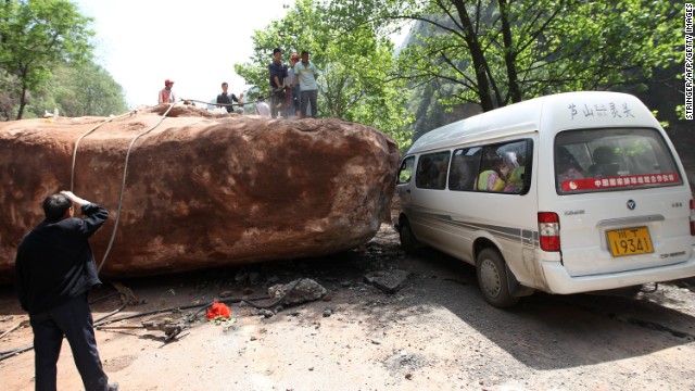 People attempt to move a huge rock blocking the road to Longmen township on Saturday.
