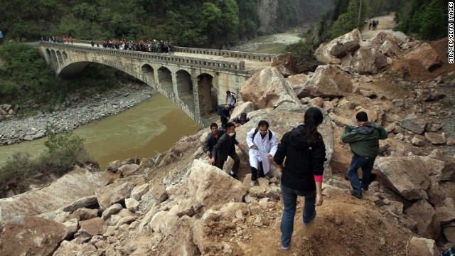 Survivors and rescuers make their way along a damaged area in Lushan on Sunday.