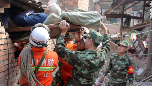 Rescuers carry a paralyzed patient from a collapsed house on Sunday in Qingren township. 