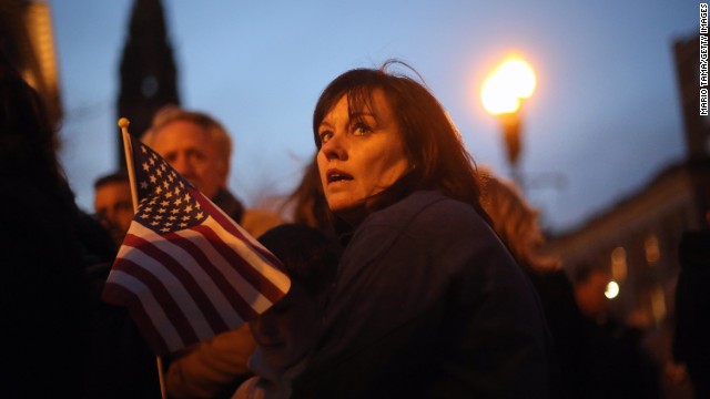 A woman holds an American flag at a makeshift memorial on April 20, near the scene of the Boston Marathon explosions.