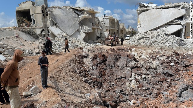 People walk past destroyed houses in the northern Syrian town of Azaz on Sunday, April 21. 