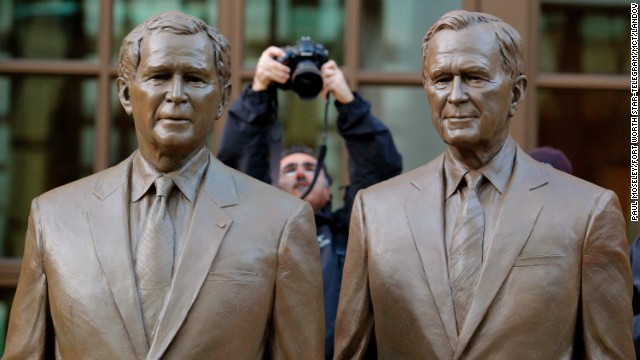 A photographer makes a photo of the two bronze statues of former Presidents George W. Bush and his father, George H.W. Bush, in a courtyard at the Center.