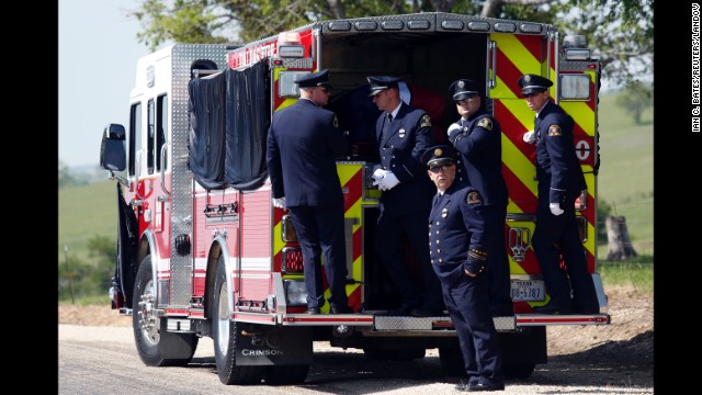 Firefighters stand on the back of a firetruck that transported Harris' body to the Bold Springs Cemetery in West on April 24.