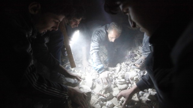Searchers use a flashlight as they look for survivors among the rubble created by what activists say was a missile attack from the Syrian regime, in Raqqa province, Syria, on April 25. 