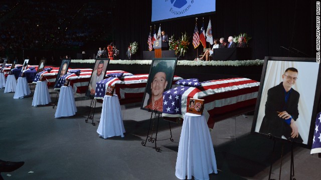 Photos of the fallen firefighters stand next to their coffins at the memorial on April 25.