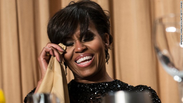 Michelle Obama dabs her eyes while laughing during the dinner