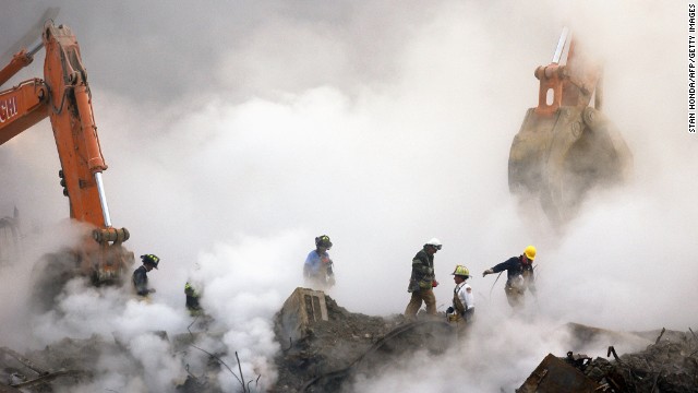 Firefighters make their way over the ruins through clouds of smoke at ground zero on October 11, 2001.