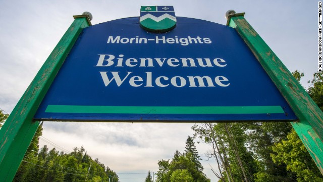 A sign reading "Welcome" in French and English stands at the entrance to Morin-Heights, a tourist town in the Laurentian Mountains region of Quebec, Canada. In Quebec, French must be the predominant language on signs, retail or food service employees always greet customers in French, and there are laws dictating whether parents can send their children to English or French school.