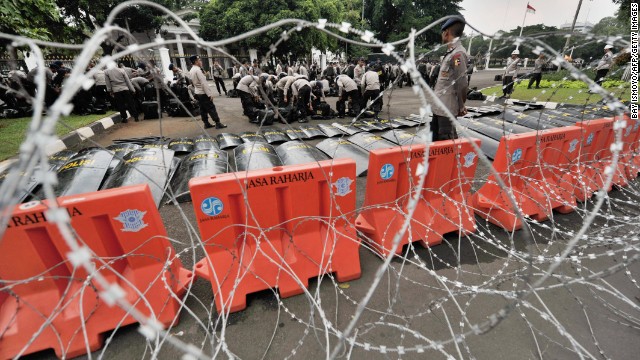 Police prepare behind a line of barbed wire before thousands of Indonesian workers arrive outside the presidential palace in Jakarta.