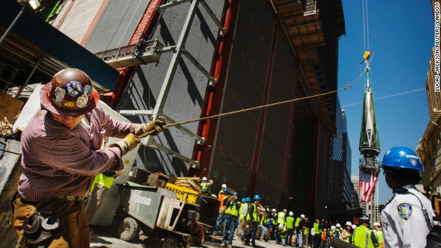 An ironworker uses a line to steady the final piece of the spire.