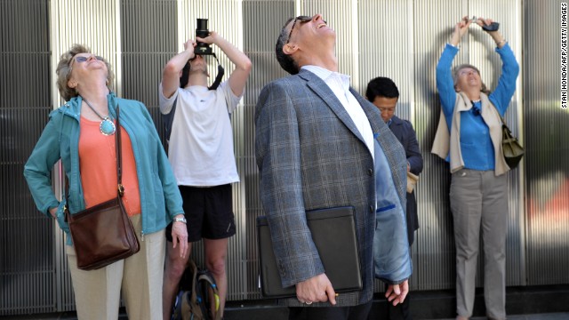 People watch as the final section of the spire is raised to the top of One World Trade Center.